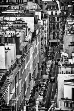 Fototapeta Black and white photo of Paris buildings, view from the roof. Streetscene viewed from above. Typical view to Paris roofs and its chimneys.