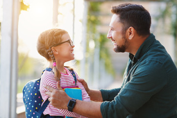 first day at school. father leads  little child school girl in first grade.
