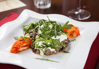 Beef with white sauce and rucola leaves with tomatoes