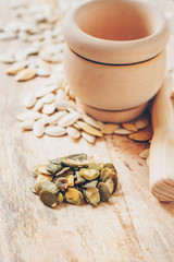 Pumpkin seeds peeled and uncleaned on a wooden board, wooden mortar