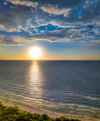Ein wunderschöner Sonnenuntergang über dem Meer mit weißen Sand von Strand im Vordergrund als hochkant Panorama als Aerial, Luftbild, die Ostsee von ihrer schönsten Seite