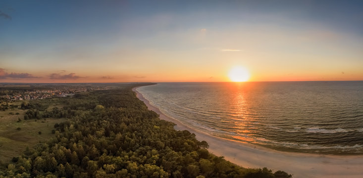 A fascinating red colored, clear sunset at a white beach of the Baltic Sea made by a drone up in the air