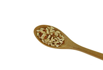 Integral, brown rice pile in a wooden spoon isolated on white background.
