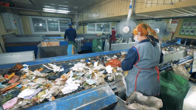 Plant workers sort garbage for recycling in a waste recycling plant.