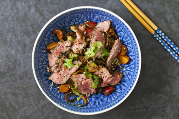 Asian stir fry beef fillet with rice noodles, bok choi, zucchini, radishes and sesame seeds