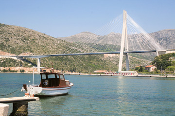 Fototapeta premium Boats on the quay of Dubrovnik port, on the Croatian coast of the Adriatic sea, with the Most Franjo Tudjman bridge in the background. Dubrovnik is one of the landmarks of Croatian Tourism