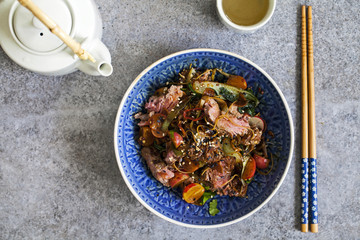 Asian stir fry beef fillet with rice noodles, bok choi, zucchini, radishes and sesame seeds