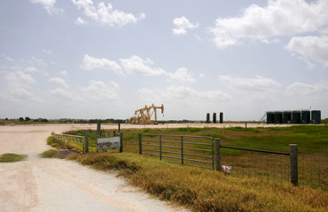 Fototapeta premium Three rocking horses and storage tanks in a Texas oilfield 