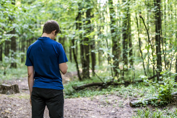 young man in blue t-shirt walk and look around the autumn forest