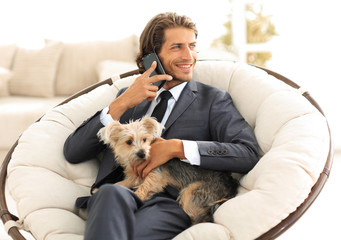 successful businessman holds his dog and pet and talks on the smartphone