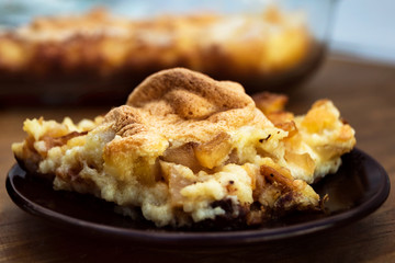 Casserole of semolina with cottage cheese and apples close-up on a round plate.
