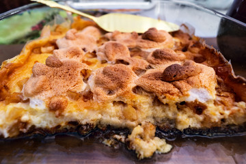 Casserole with sliced apples, cottage cheese, semolina and cheese in a glass container for baking.