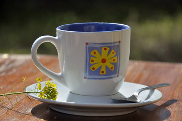 Coffee cup on a wooden table, in summer outdoors.