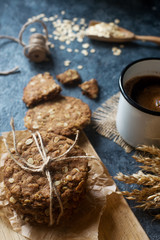 Homemade oatmeal fitness cookies and black coffee on wooden board and dark stone talbe. Healthy lifestyle, vegan breakfast concept, selective focus