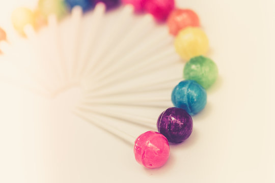 Rainbow design of sweet colorful lollipops against white background with vintage retro tone