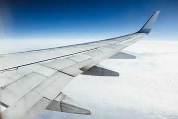 airplane wing against clouds and blue sky background