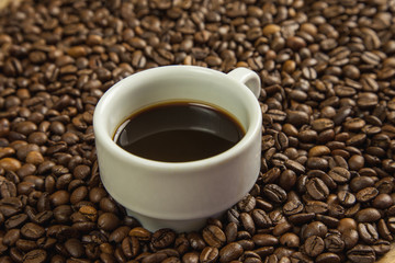 Granos de café rodeando a una taza