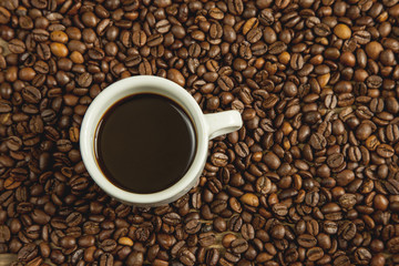 Taza de café caliente rodeada de café en grano recién tostado
