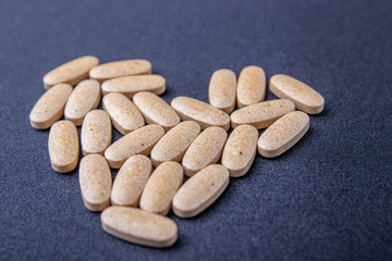 oval brown pills on a dark blue background in the form of the heart