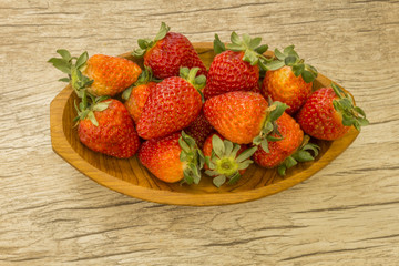 wooden bowl with strawberries and dulce de letche in spoon at wooden background