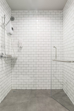 White Bathroom Interior And Shower With Tile And Glass Shower Doors In New Luxury Home