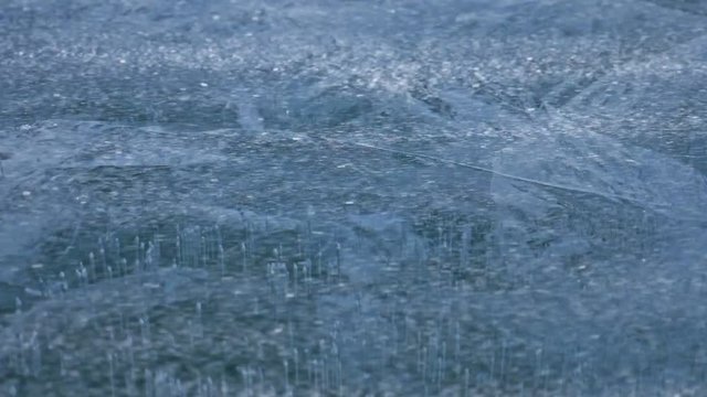 Snow is flying over surface of ice. Snowflakes fly on ice of Lake Baikal. Ice is very beautiful with unusual unique cracks. Snow sparkles and glows in red. Shooting slow motion 180fps. Picture at