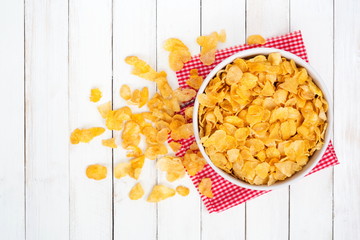 Cornflake cereals in white bowl on white wooden desk,Top view.