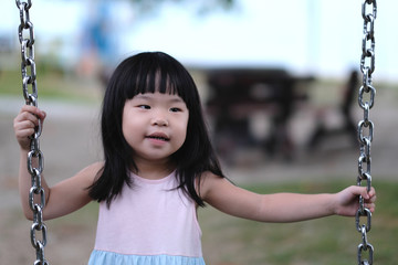 Portrait of a little asian girl in swing at outdoors park