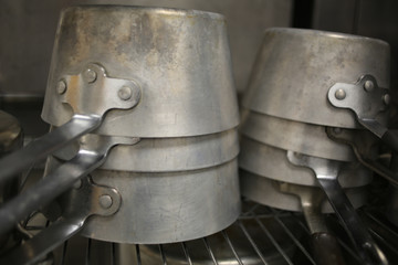 Stainless Steel Pots Stacked on a Metal Rack in an Industrial Catering Kitchen
