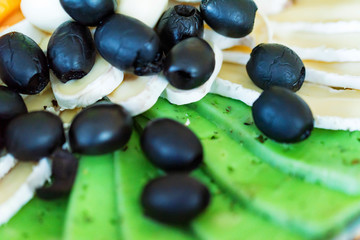 Cheese plate with fresh olives close up
