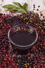 Bunch of elderberry with juice on old wooden background, healthy nutrition
