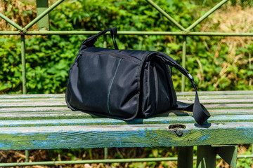 Bag on wooden bench at a railroad station at countryside