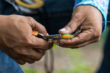 Angler tying a fishing hook to rubber worm lure