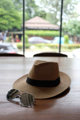 Brown hat and sunglasses on a wooden table