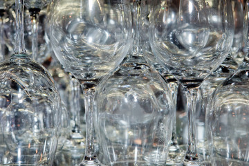 A multitude of wine glasses in a bar standing alternated with glasses upside down ready for consumption