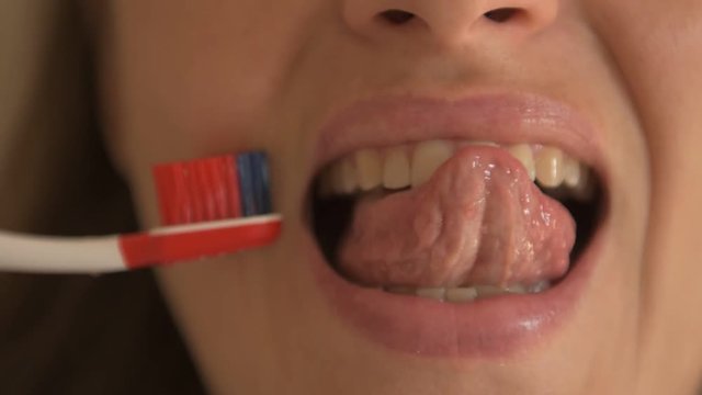 Young girl with beautiful white teeth squeezes toothpaste out of tube, cleans her teeth. Close up