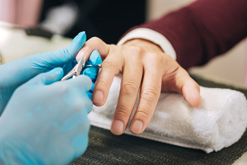 Obraz na płótnie Canvas Manicure procedure. Close up of female hands dressing in gloves and utilizing cuticle grip