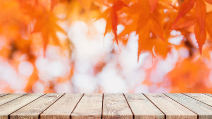 Empty wood table top and blurred autumn tree and red leaf background - can used for display or...