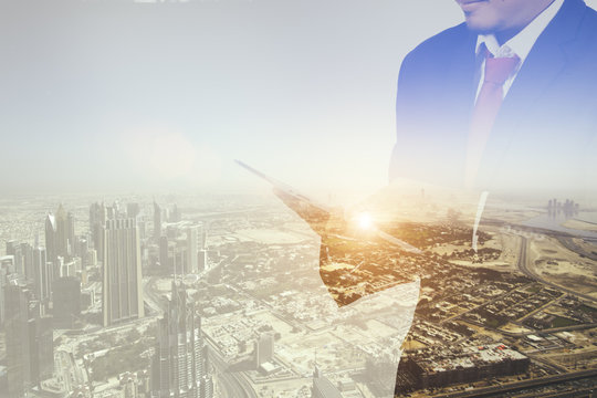 Double exposure of a businessman and a city using a tablet, cityascape and network concept