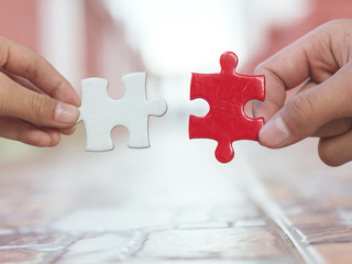 hands holding piece of gold and red jigsaw puzzle