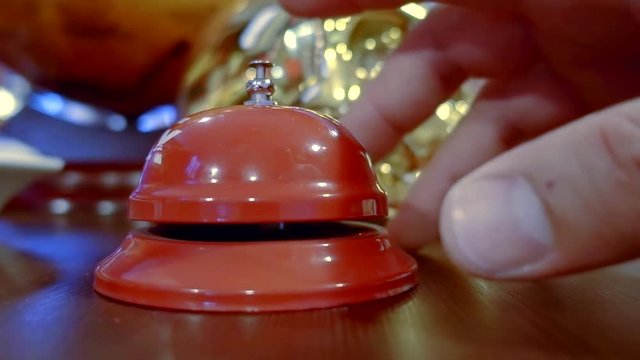 visitor of hotel is calling by bell for staff on reception, close-up view of hand