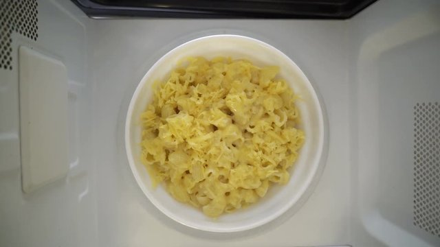 Making microwave meal. Macaroni and cheese in bowl microwaving top view.