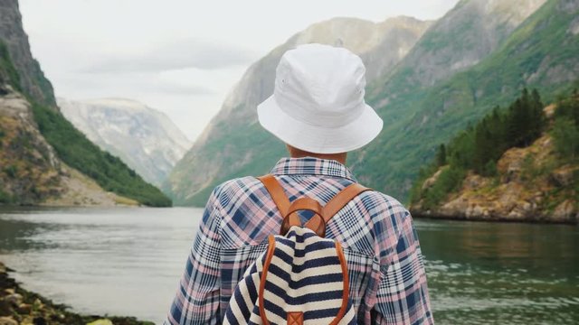 A woman with a backpack behind her back looks at the majestic fjord in Norway. Travel and Tourism in Scandinavia concept