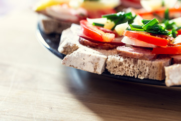 Delicious healthy homemade sandwiches with vegetables and cold cuts on the plate. Shallow depth of focus.