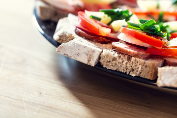 Delicious healthy homemade sandwiches with vegetables and cold cuts on the plate. Shallow depth of focus.