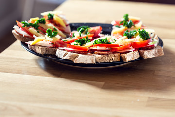 Delicious healthy homemade sandwiches with vegetables and cold cuts on the plate. Shallow depth of focus.