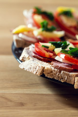 Delicious healthy homemade sandwiches with vegetables and cold cuts on the plate. Shallow depth of focus.