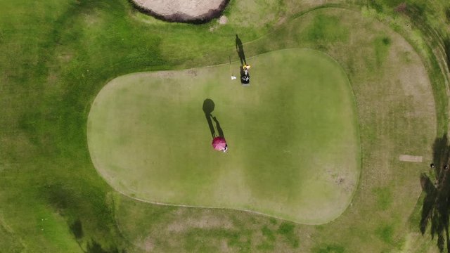 Golfer putting golf ball on the green golf - Aerial top view photo from flying drone