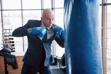 Fototapeta na wymiar An angry bald businessman beats a boxing pear in the gym. concept of anger management