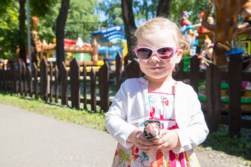 Small girl in the fun park with carousel